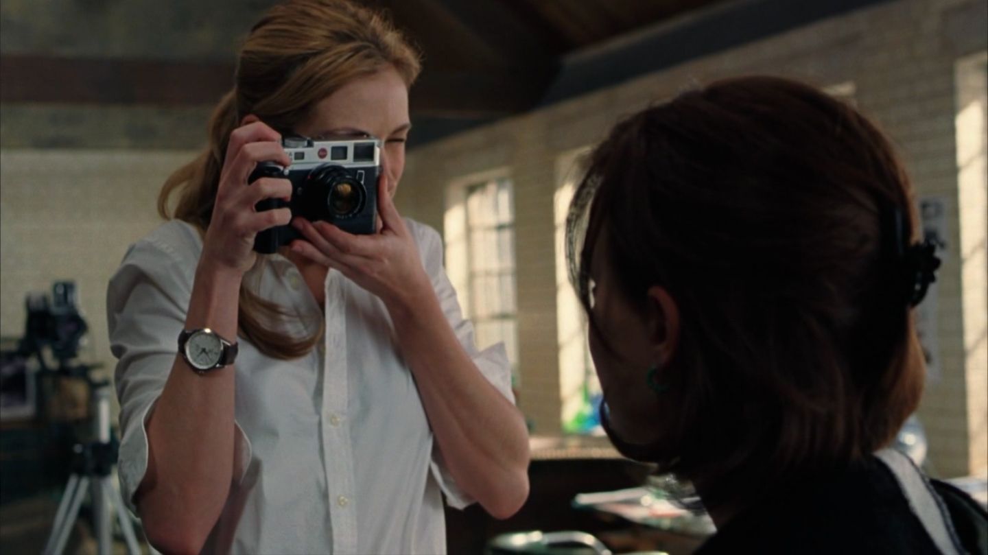 Anna, personagem interpretada pela atriz Julia Roberts, com uma câmera na mão e tirando foto em cena do filme Closer, de 2004. 