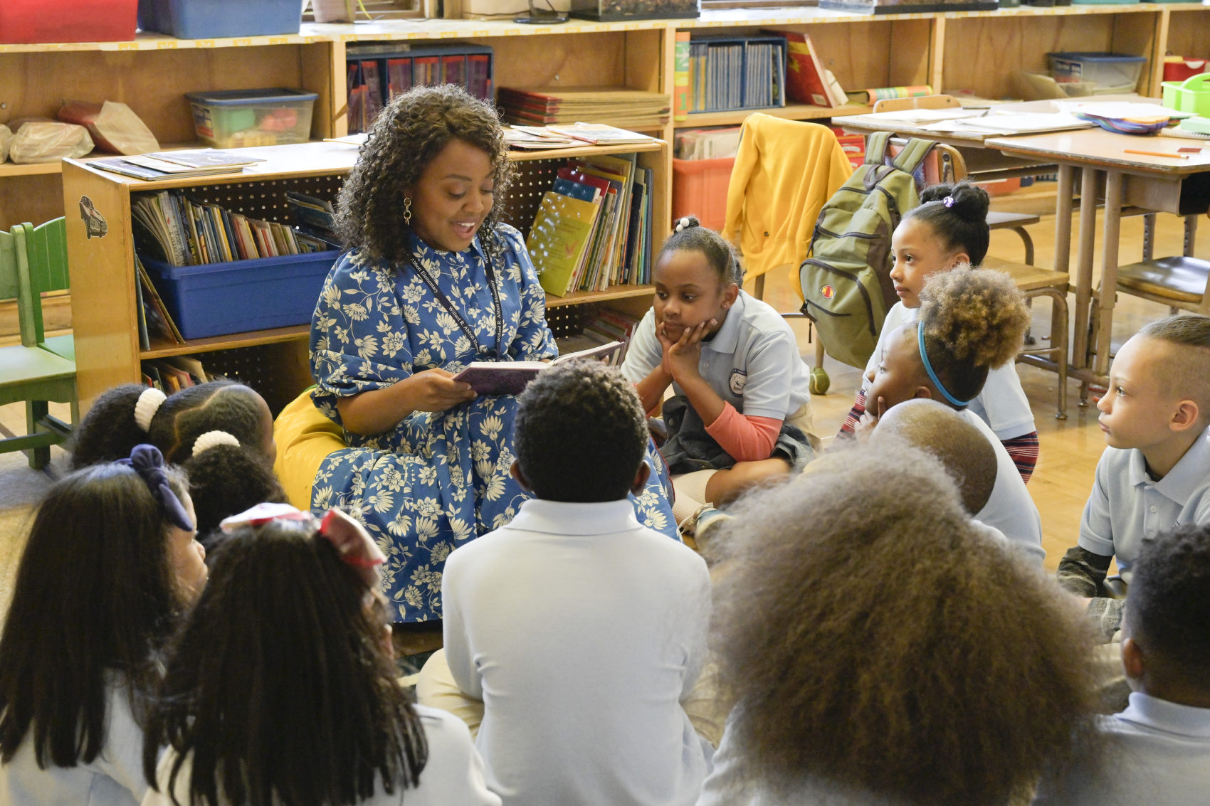Quinta Brunson como Janine em uma sala de aula lendo uma história para os seus alunos ao redor