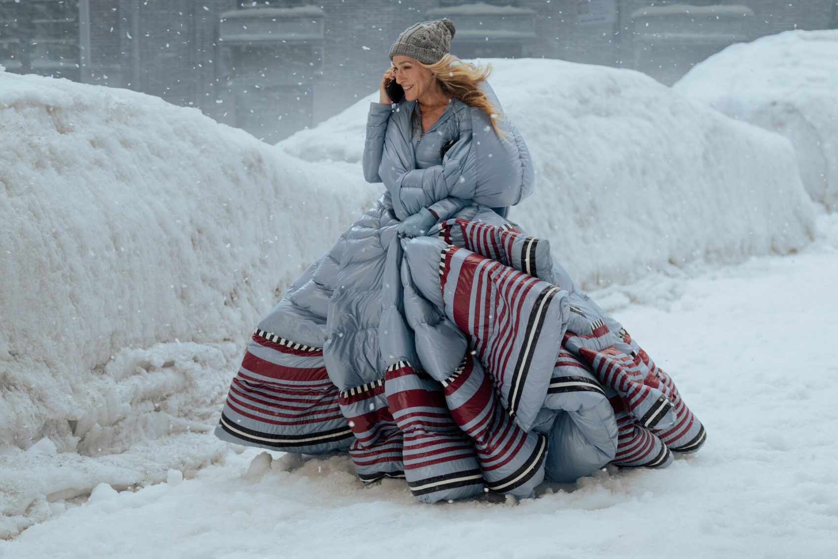 Mulher caminha na rua em meio a uma nevasca usando um vestido de festa feito de edredom.