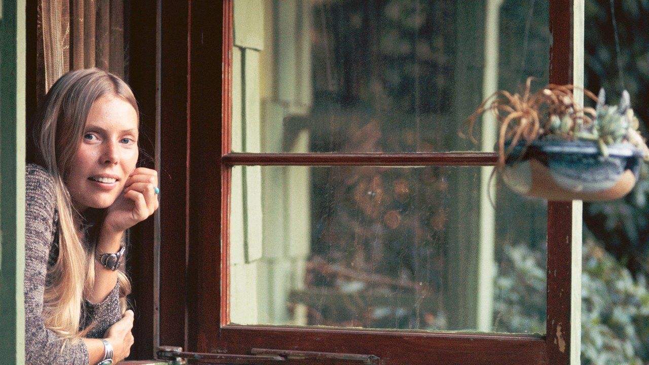 A icônica imagem de Joni Mitchell olhando pela janela de seu quarto em Laurel Canyon, em 1970, capturada pelo fotógrafo Joel Bernstein.