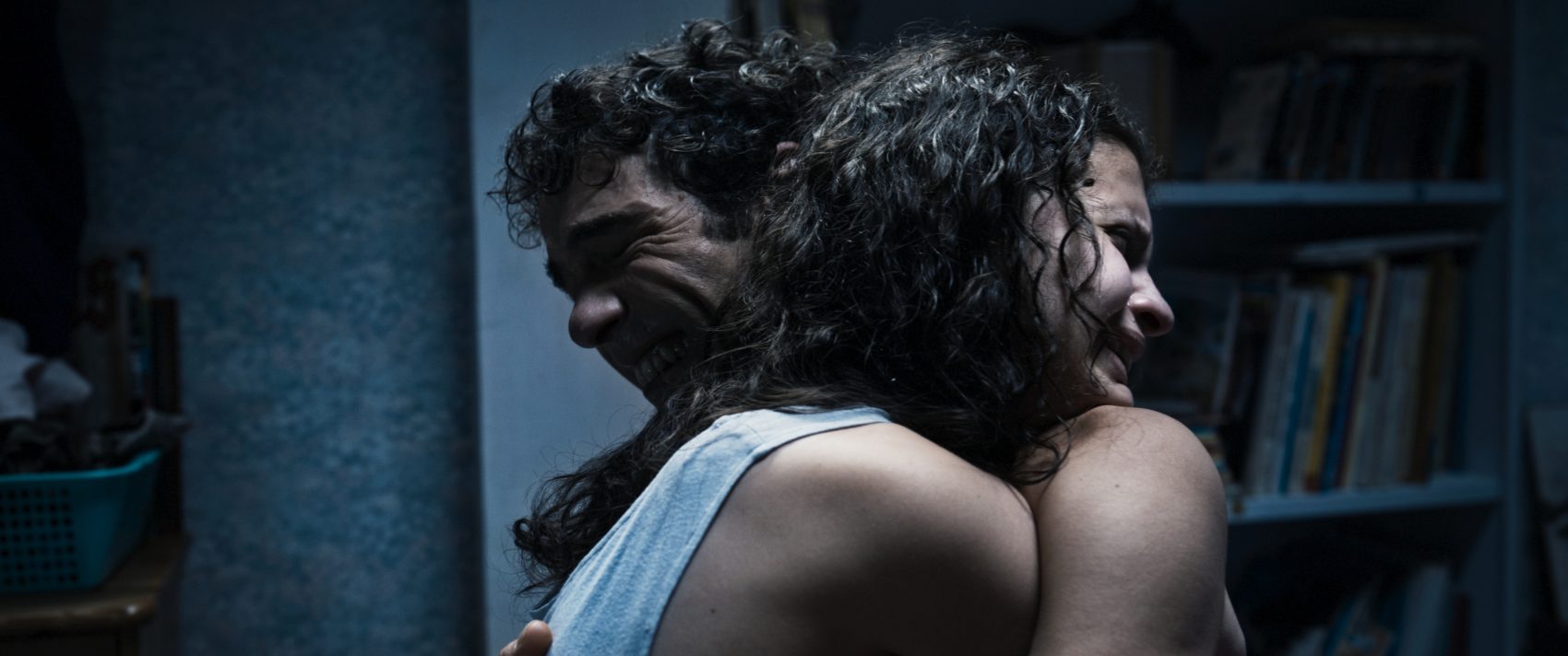 Cena de um homem e uma mulher se abraçando, destacando uma conexão emocional intensa, em ambiente interno com iluminação suave.