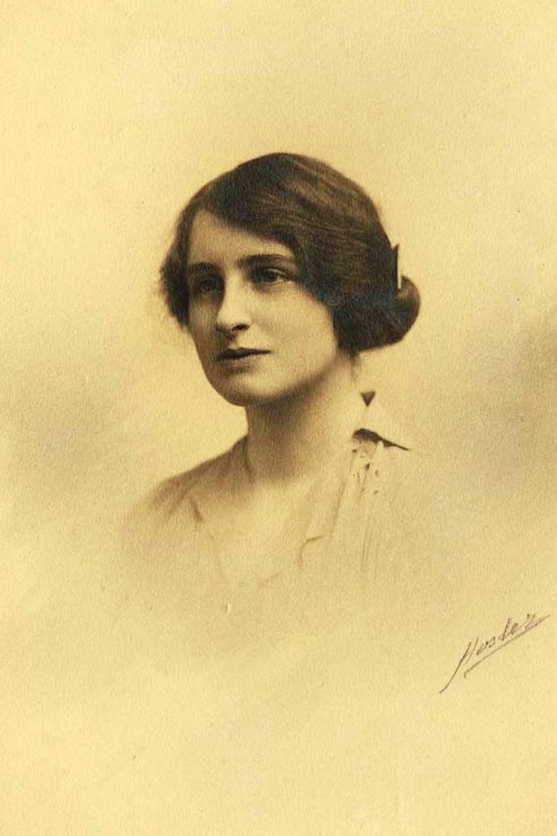 Retrato clássico de uma mulher com cabelo castanho escuro e penteado vintage, com expressão serena, em tom sépia.