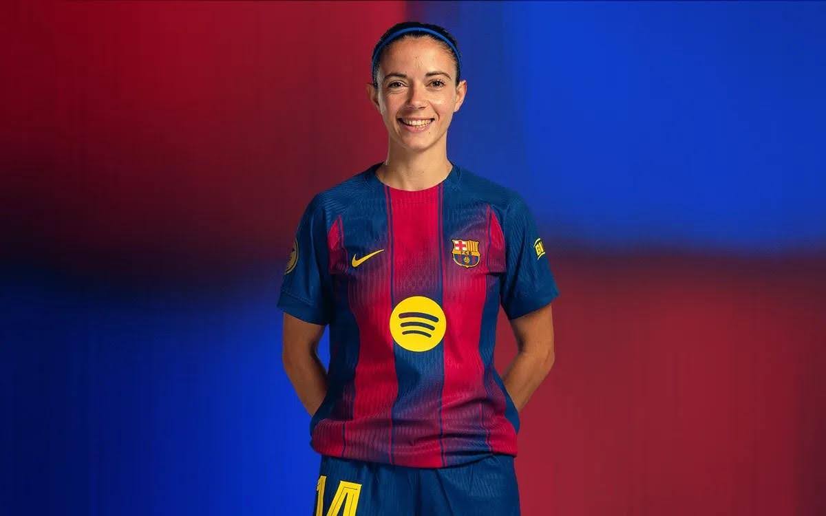 Jogadora de futebol com uniforme do Barcelona e logotipo do Spotify, sorrindo.