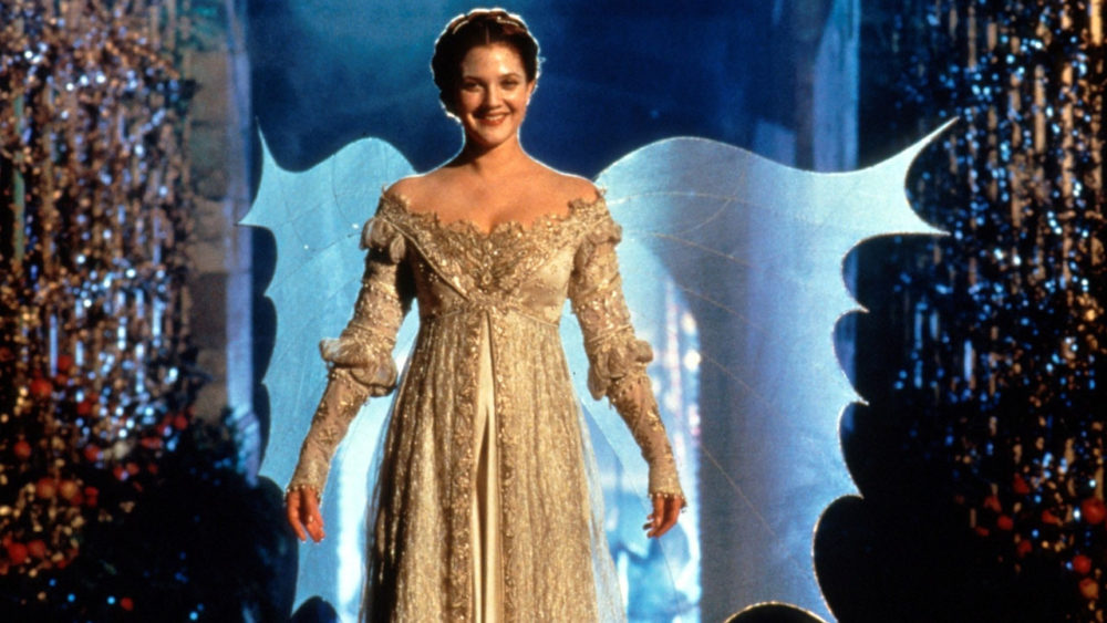 Cena do filme "Para Sempre Cinderela", onde uma personagem feminina veste um vestido dourado longo e fica em destaque em um cenário com luzes brilhantes e decorações festivas.